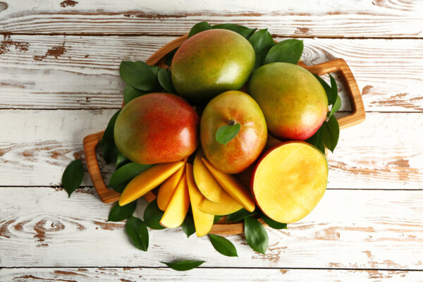 Board with tasty fresh mango on wooden table